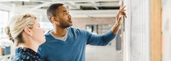 Image of two people pointing at a board